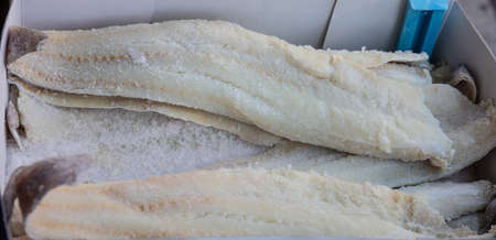 Salted dried codfish in a carton box, background, texture. Closeup view