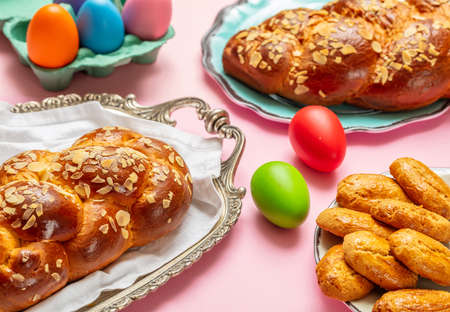 Easter eggs and tsoureki braid, greek easter sweet bread, on pink color background