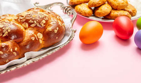 Easter eggs and tsoureki braid, greek easter sweet bread, on pink color background