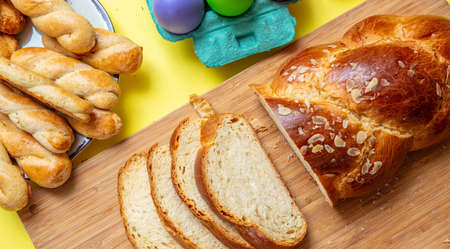 Easter eggs and sliced tsoureki braid, greek easter sweet bread, on wood, yellow color background, top viewの写真素材