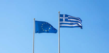Greece and EU relations. Greek and European Union flags waving on clear blue skyの写真素材