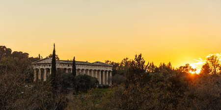 Athens Greece. Hephaestus temple at sunrise time, sun rising against orange color sky. View from Monastiraki areaの写真素材