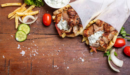 Gyro pita, shawarma, take away, street food. Two pita bread wraps with meat, traditional greek turkish food on wooden table, copy spaceの写真素材
