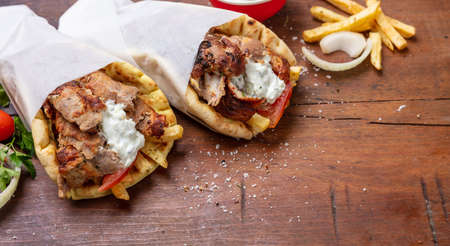 Gyro pita, shawarma, take away, street food. Two pita bread wraps with meat, traditional greek turkish food on wooden table, copy spaceの写真素材