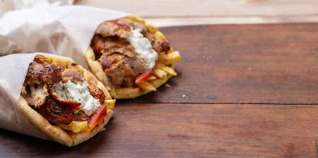 Gyro pita, shawarma, take away, street food. Two pita bread wraps with meat, traditional greek turkish food on wooden tableの写真素材