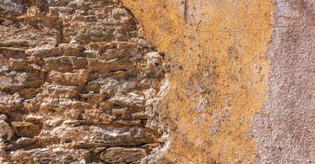 Old, distressed stone wall, building facade. Painted orange color, faded masonry texture background
