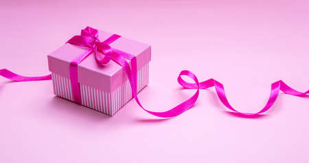 Pink gift box. Present with bright pink ribbon bow on pink background. Womens or mothers day concept.の写真素材