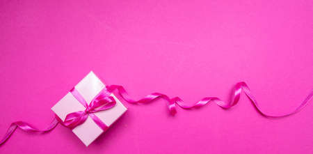 Pink gift box. Present with pink ribbon bow on bright pink background, banner. Womens or mothers day concept.の写真素材
