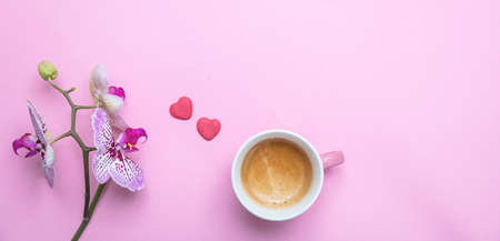 Women, mothers day concept. Orchids flowers purple white color and a cup of coffee against pink background, copy space.の写真素材