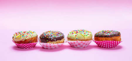 Cupcakes on pink. Mini cakes with icing and colorful sprinkles on pink background, closeup view,...