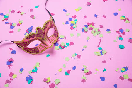 Carnival, birthday party. Female venetian mask and colorful confetti on pink backgroundの写真素材