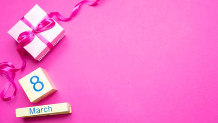 Womens day concept. Gift box with ribbon and date March 8th on wooden cubes against pink background,...
