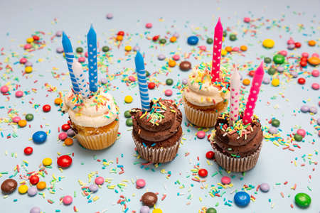 Birthday cupcakes on blue pastel background. Four cupcakes vanilla and chocolate with blue and pink...