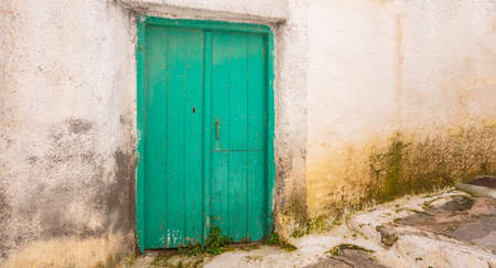 Greece, Kea island. Traditional wooden door bright green color on whitewashed stone wall in capital city of Ioulis.の写真素材