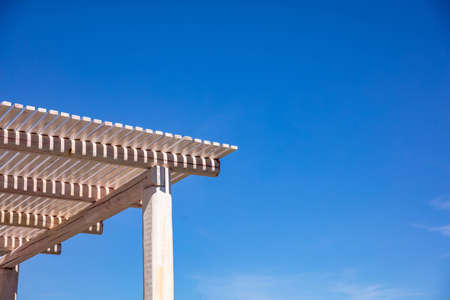 White wooden pergola for sun protection, clear blue sky background, copy space, closeup view