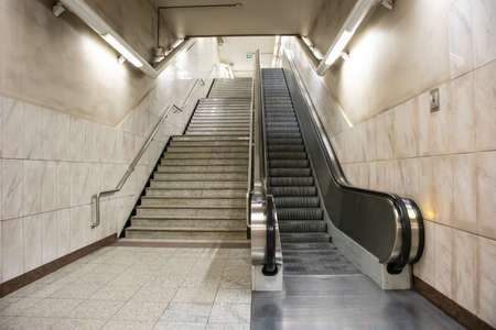 April 14, 2019. Greece, Athens. Empty electric escalators and stairway at a metro station in the city center. Marble tiled wall and floor, stainless steel railings and equipmentのeditorial素材
