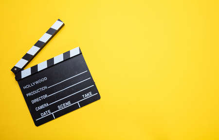 Cinama film concept. Movie clapper board on yellow color background, copy space