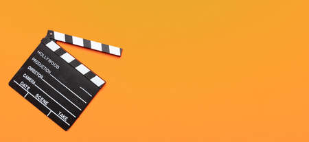 Cinama film concept. Movie clapper board on orange color background, banner, copy spaceの写真素材