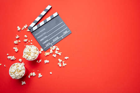 Cinema for two concept. Fresh salty pop corn and movie clapper board, red color background, top viewの写真素材