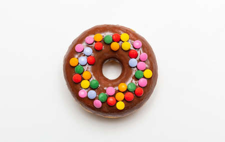Chocolate doughnut decorated with colorful smarties isolated on white color background, top close up...