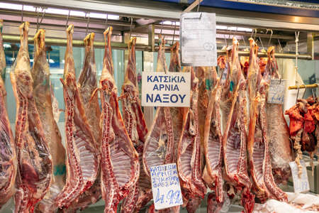 April 28, 2019. Athens, Greece. Greek butcher shop concept. Whole lambs are hanging on hooks out of market.のeditorial素材
