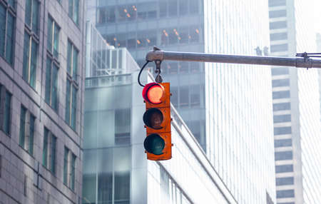 Red traffic lights for cars hanging in the city center, blur office buildings backgroundの写真素材