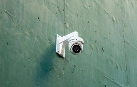 CCTV Security system. Surveillance Camera on a green color wall background, low angle closeup view