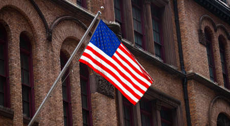 USA symbol in New York streets. American flag in Manhattan downtown, old classical building facade...