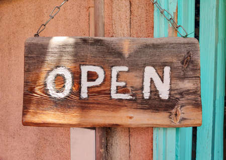 Open text on wooden sign board hanged with a metal chain on a buildings facade, close up viewの写真素材