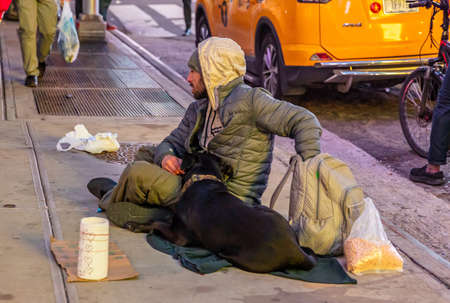 USA, New York. May 3, 2019. Homeless man and a dog sitting on the sidewalk, asking for help, Manhattan downtownのeditorial素材