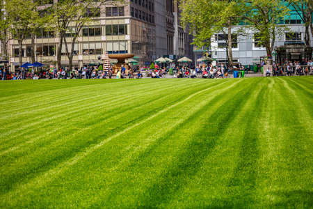 New York, Manhattan United States, May 2nd, 2019. Springtime in Bryant park. People relaxing, green lawn and trees, buildings backgroundのeditorial素材
