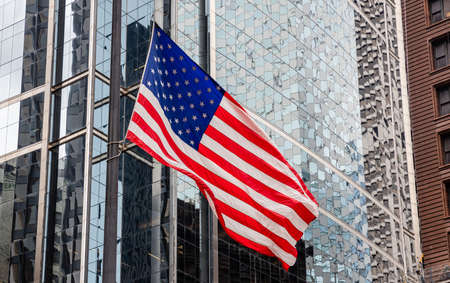 USA symbol. American flag waving in Chicago, Illinois downtown. Highrise gass buildings background.の写真素材
