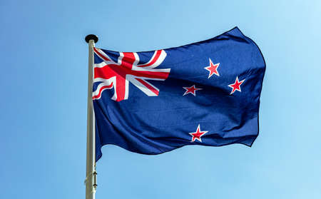 New Zealand flag, New Zealand national symbol waving against clear blue sky, sunny dayの写真素材