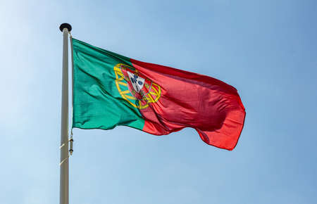 Portugal flag, Portuguese national symbol waving against clear blue sky, sunny dayの写真素材