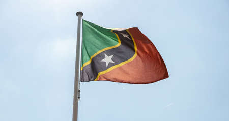 Saint Kitts and Nevis flag, National symbol waving against clear blue sky, sunny dayの写真素材