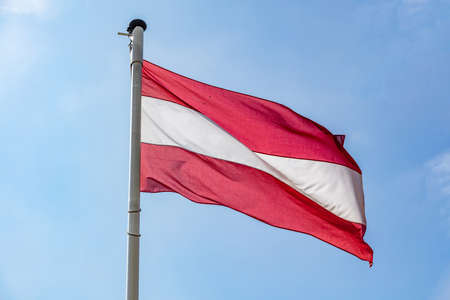 Austria flag, Austrian national symbol waving against clear blue sky, sunny dayの写真素材