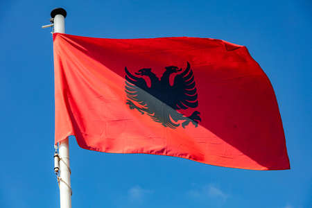 Albania flag, Albanian national symbol waving against clear blue sky, sunny dayの写真素材