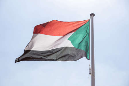 Sudan flag, National symbol waving against clear blue sky, sunny dayの写真素材