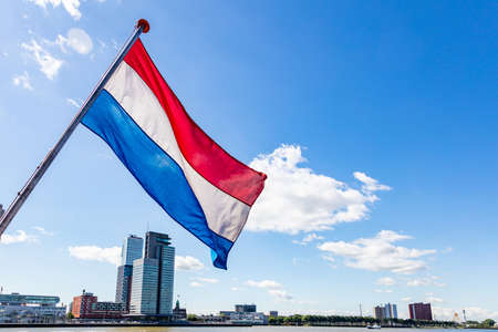 Netherlands flag waving, Highrise buildings background, sunny day in Rotterdam city centerの写真素材