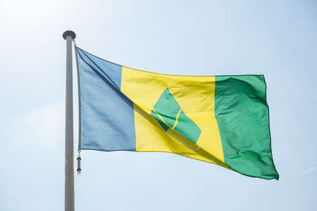 Saint Vincent and the Grenadines flag, National symbol waving against clear blue sky, sunny dayの写真素材