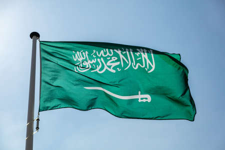Saudi Arabia flag, National symbol waving against clear blue sky, sunny dayの写真素材