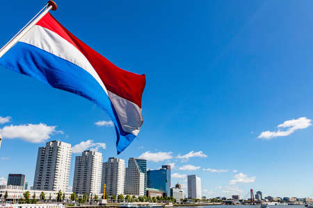 Netherlands flag waving, Highrise buildings background, sunny day in Rotterdam city centerの写真素材