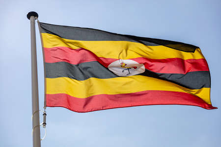 Uganda flag, National symbol waving against clear blue sky, sunny dayの写真素材