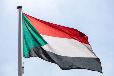 Sudan flag, National symbol waving against clear blue sky, sunny dayの写真素材