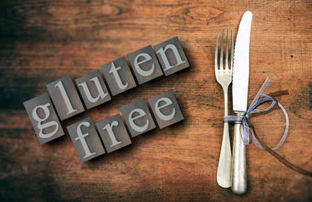 Gluten free menu, healthy eating concept. Gluten-free text and cutlery set on rustic wooden table, top view. 3d illustrationの写真素材