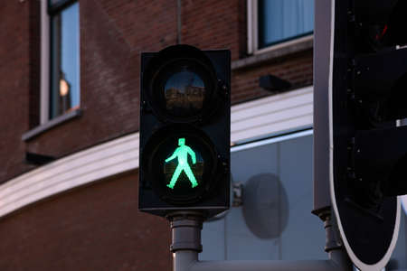 Go sign, green traffic light for pedestrians against building facade background. Pedestrian crossing with safety conceptの写真素材
