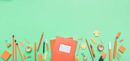 Back to school. School supplies orange color on green pastel background, banner, top view, copy...