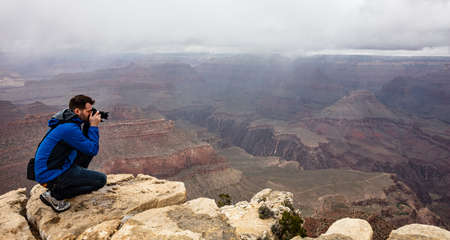 Grand Canyon, Arizona, USA. May 22, 2019. Man taking photos of the red rocks gorge, cloudy skyのeditorial素材