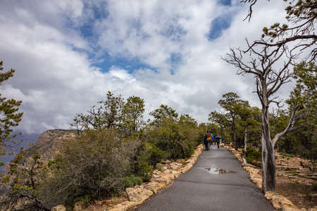 Grand Canyon, Arizona, USA. May 22, 2019. Group of people walking on the path and looking at the red rocks gorge, cloudy skyのeditorial素材