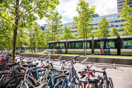 Rotterdam, Netherlands. July 1, 2019. Bikes parked on a sidewalk and a tram is moving in the city centerのeditorial素材